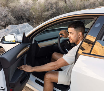 A man opening the door on the driver seat of a Tesla car